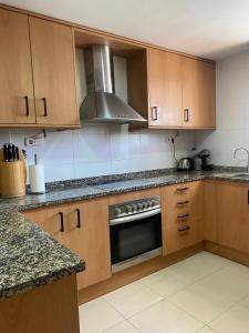 a kitchen with wooden cabinets and a stove top oven at Wonderful townhouse on Sa Boadella beach in Lloret de Mar