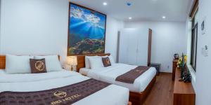 a hotel room with two beds and a painting on the wall at Big Hotel Lào Cai in Lao Cai