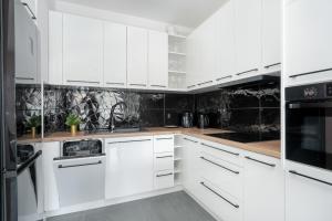 una cocina blanca con armarios blancos y electrodomésticos negros en City Center Apartments with GYM & FREE GARAGE Poznań by Renters, en Poznan
