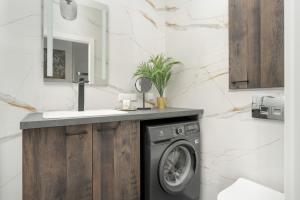 a bathroom with a washing machine under a sink at City Center Apartments with GYM & FREE GARAGE Poznań by Renters in Poznań