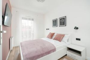 a white bedroom with a bed and a tv at City Center Apartments with GYM & FREE GARAGE Poznań by Renters in Poznań