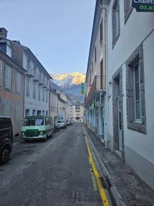 una strada cittadina vuota con auto, edifici e montagne di Loft 6 couchages (4+2) a Cauterets