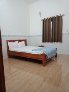 ein Schlafzimmer mit einem Holzbett und einem Fenster in der Unterkunft Tam Ky XO Hotel in Tam Kỳ