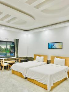 a bedroom with two beds and a table with a desk at Khách sạn Khang Điền 2 in Xóm Phước Mỹ