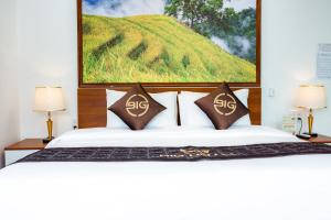 a bedroom with a bed with a painting on the wall at Big Hotel Lào Cai in Lao Cai