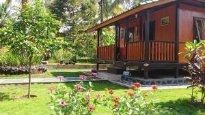 a small cabin in a garden with flowers at Pondok Jati Mulo Jembrana in Jembrana +5 photos