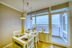una sala da pranzo con tavolo, sedie e una grande finestra di Ferienpark - Haus E, App 0E0708 a Heiligenhafen