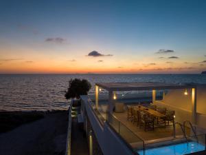 a house with a view of the ocean at sunset at Aegean Melody Suites in Vlychada