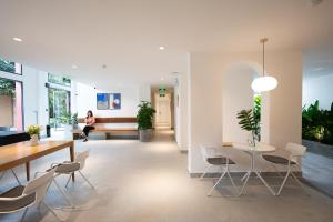 a room with a table and chairs and a woman sitting on a couch at M Village Living 59 Thảo Điền in Ho Chi Minh City