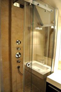 una ducha con una puerta de cristal junto a un lavabo en Argenson, en París