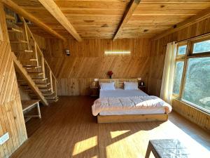 ein Schlafzimmer mit einem Bett in einer Holzhütte in der Unterkunft Himalayan Mountain View Cottage Deohari in Sainj