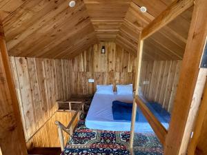 ein kleines Zimmer mit einem Bett in einer Holzhütte in der Unterkunft Himalayan Mountain View Cottage Deohari in Sainj