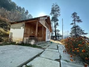 ein kleines Gebäude neben einem Blumenfeld in der Unterkunft Himalayan Mountain View Cottage Deohari in Sainj