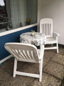 twee witte stoelen en een tafel met een kaars erop bij Schwalbe - Tripp in Westerland