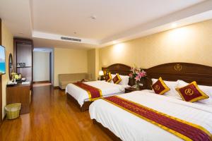 um quarto de hotel com duas camas e flores nele em Regalia Nha Trang em Nha Trang