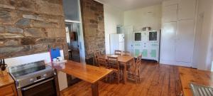 a kitchen and dining room with a wooden table at The Sunday School Cottage on the Heysen Trail in Burra