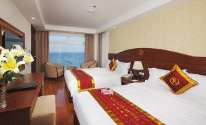 um quarto de hotel com duas camas e uma mesa com flores em Regalia Nha Trang em Nha Trang