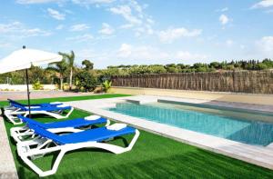 einen Pool mit Liegestühlen und einem Sonnenschirm in der Unterkunft Villa Montenmedio Paula in El Soto