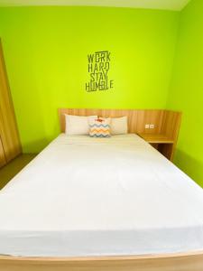 a bedroom with a large bed with a green wall at Behomy Maxley Lippo Karawaci in Tangerang