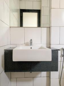 a white sink in a bathroom with a mirror at Behomy Maxley Lippo Karawaci in Tangerang