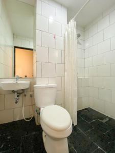 a bathroom with a white toilet and a sink at Behomy Maxley Lippo Karawaci in Tangerang