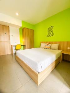 um quarto com uma cama grande e uma parede verde em Behomy Maxley Lippo Karawaci em Tangerang