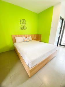 uma cama num quarto com uma parede verde em Behomy Maxley Lippo Karawaci em Tangerang