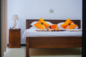 a bed with orange and yellow pillows on it at The Glade in Weligama