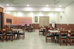 comedor con mesas y sillas de madera en The Corbett Greens, en Rāmnagar