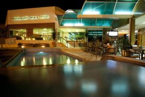 Indaiá Park Hotel في كامبو غراندي: مسبح امام مطعم في الليل