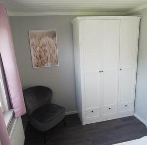 a bedroom with a white cabinet and a chair at Boddenferienhaus - 11 Seemannsgarn in Schaprode