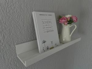 a book and a vase of flowers on a shelf at Boddenferienhaus - 11 Seemannsgarn in Schaprode