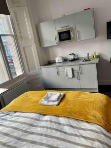a bed with a yellow blanket and a kitchen at Small studio in Notting Hill in London