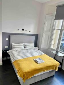 a bedroom with a bed with a yellow blanket on it at Small studio in Notting Hill in London