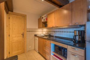 una cucina con armadi in legno e piano di lavoro nero di ArboRêve - Station de ski à pied vue montagne a Megève Altre 5 foto