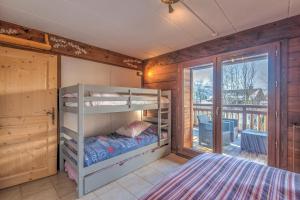 Schlafzimmer mit Etagenbetten und Balkon in der Unterkunft ArboRêve - Station de ski à pied vue montagne in Megève