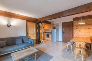 a living room with a blue couch and a table at ArboRêve - Station de ski à pied vue montagne in Megève