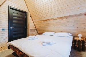 1 dormitorio con 1 cama grande y pared de madera en Cabana A-Frame Sesu, en Cîrlibaba
