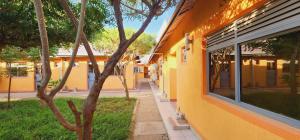 a yellow building with a tree next to a sidewalk at Quanam Woods Hotel in Lodwar