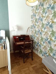 een bureau in een kamer met een muur met behang bij La Fontaine du Mas in Thiviers