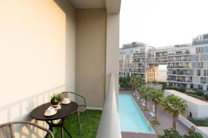 balcón con mesa y sillas y piscina en Modern 1-bedroom apartment in family-friendly residence with Swimming Pool, Gym & Free Parking., en Dubái