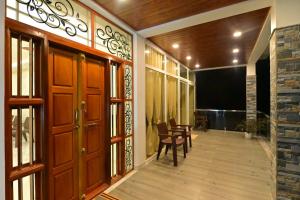 a hallway with wooden doors and a table and chairs at Gokula Homestay in Subrahmanya