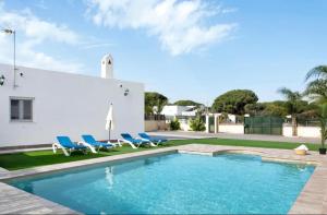 una piscina con 2 sillas azules y una casa en Villa Montenmedio Juande, en El Soto