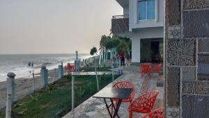 um edifício com cadeiras vermelhas e uma mesa junto à praia em Dreamers Paradise em Jaliapāra