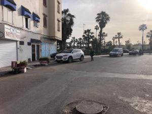 un hombre caminando por una calle con coches aparcados en élégant appartement Essaouira, en Essaouira