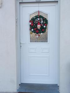 Una puerta blanca con una corona de Navidad. en gite repos et tranquillité G en Cayeux-sur-Mer