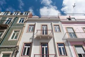 an airplane flies over a building with balconies at Amaro II - Sleek 2 bedroom apartment in Alcantara in Lisbon