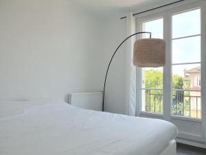 a white bedroom with a bed and a window at EXIGEHOME-Appart très lumineux aux portes de Paris in Suresnes