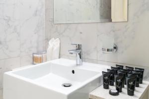 Baño blanco con lavabo y espejo en Modern 1-bedroom apartment in family-friendly residence with Swimming Pool, Gym & Free Parking., en Dubái