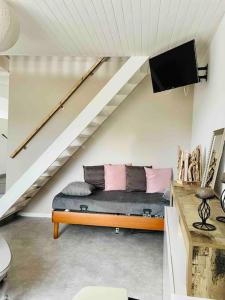 a living room with a couch under a stairs at Agréable maison de village avec balcon in Roiffieux